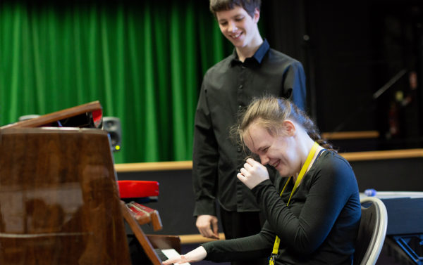 Picture of pianist Ashleigh laughing with Ben cheering her on