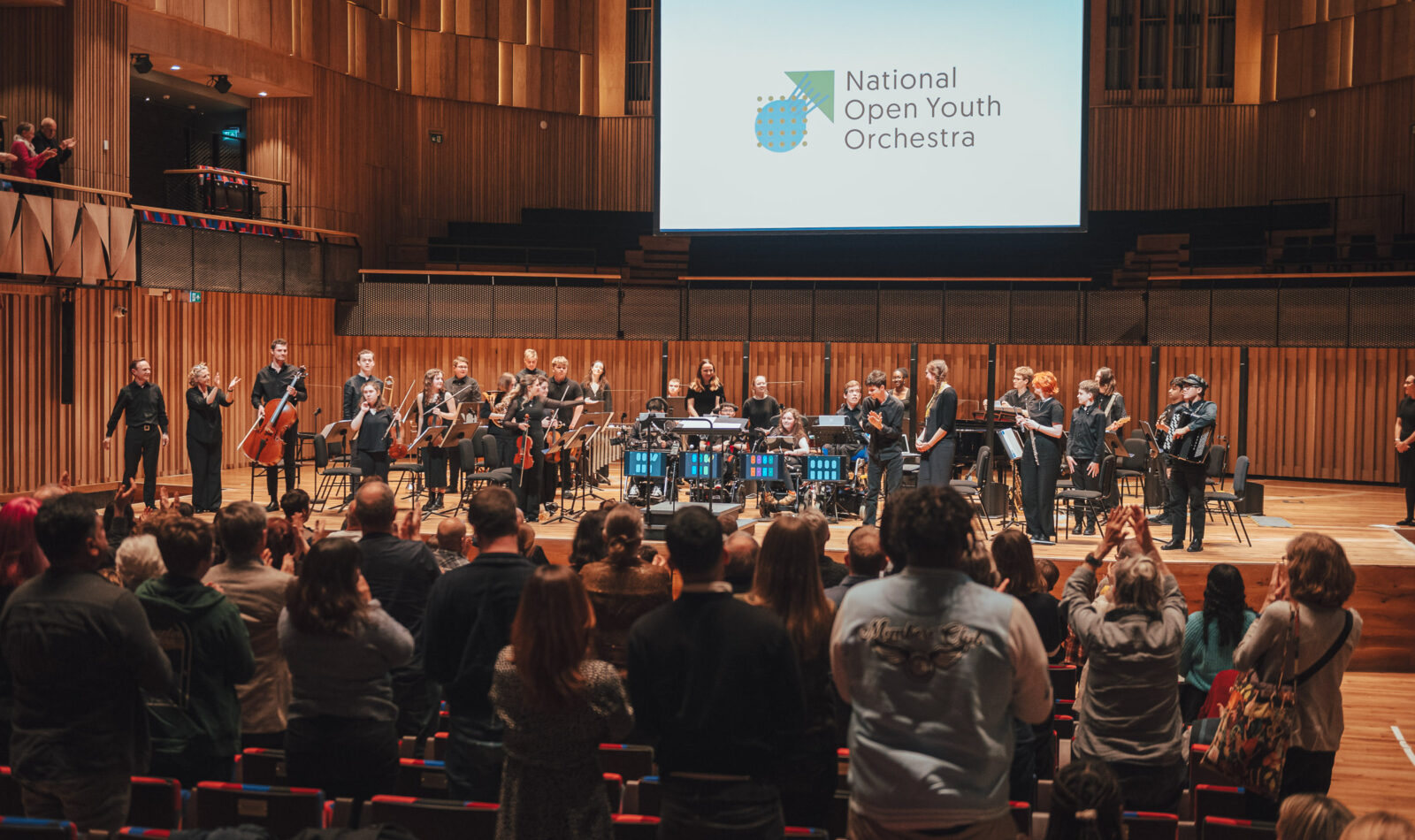 Audience members give a standing at the NOYO 2024 concert at Bristol Beacon.