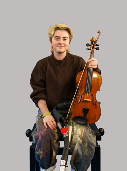 Smiling young musician sat holding a violin. He has a walking stick decorated with a heart.