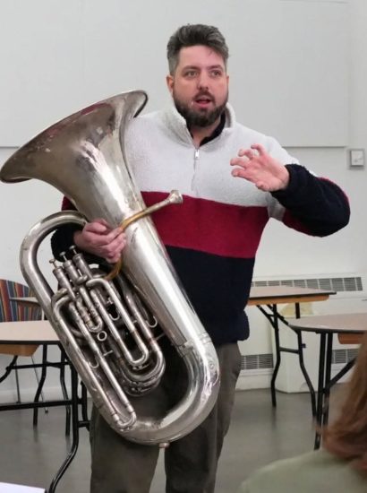 Bristol NOYO Ensemble producer, Ed stands in front of a group of musicians holding a tuba.